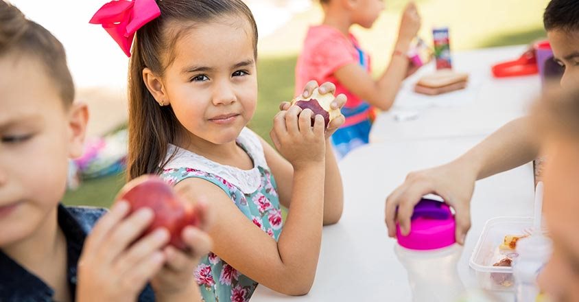 children enjoying apples at a picnic table