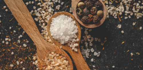 photo of spices like salt and pepper on wood table in wooden spoons