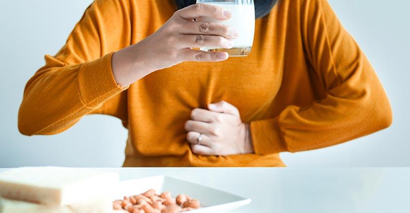 Man clenching stomach in pain with milk in hand