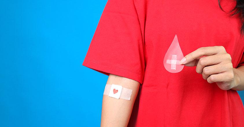 woman in red shirt with Band-Aid from giving blood