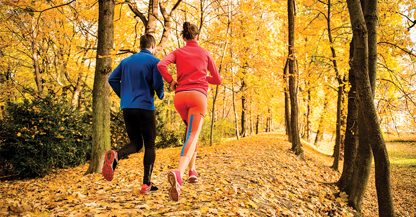 couple running on path in the autumn time