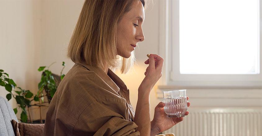 woman taking a supplement vitamin with water
