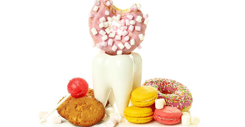 fake tooth statue with sweets surrounding, i.e. donuts, cookies, candy