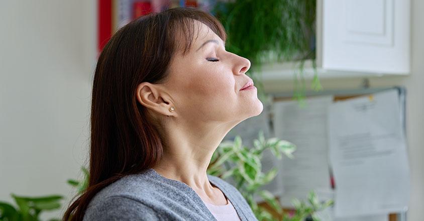 woman taking in the sunshine in a moment of peace through her window