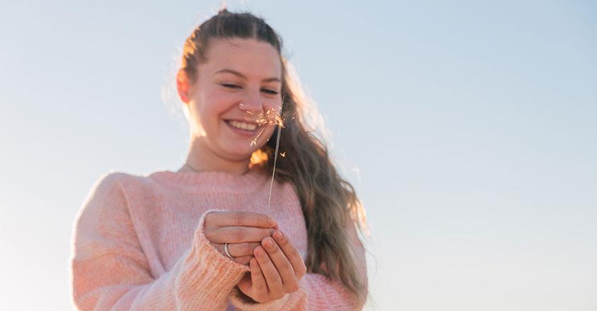 younger woman smiling with a sparkler in her hand