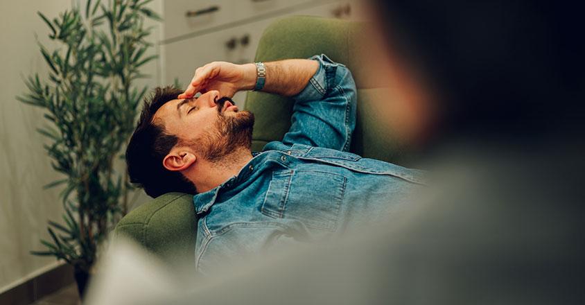 man stressed, holding his hand over his forehead