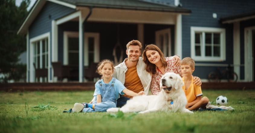 family posing for photo in their front yard with dog, two kids and parents