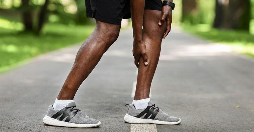 close up of man holding his calf muscle, representing a muscle cramp