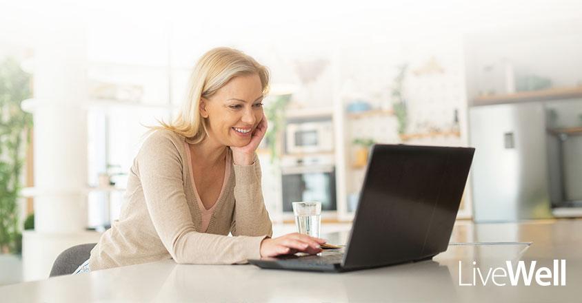 woman on her laptop, smiling in a kitchen at home