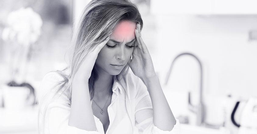 woman suffering from a migraine, a red mark on her forehead against black and white photo symbolizes pain from migraine
