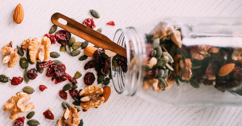 trail mix spilled over on counter with mason jar and spoon