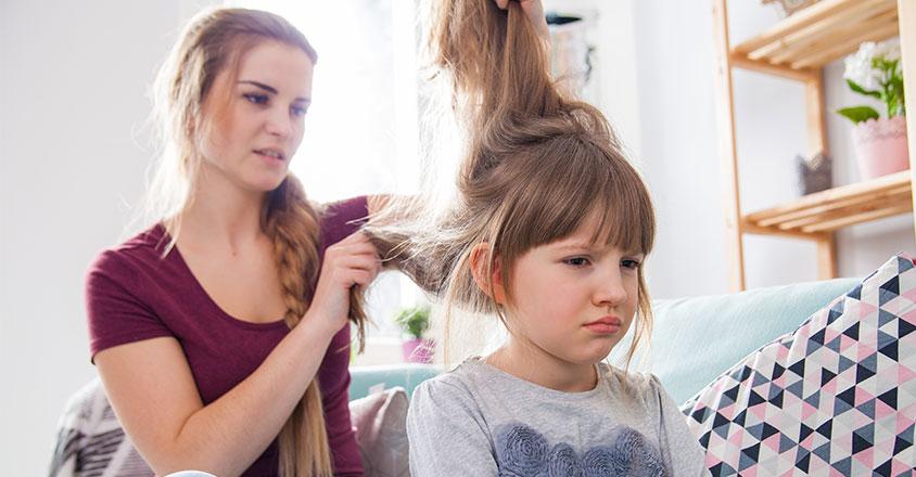Mom trying to brush out tangles in daughters hair