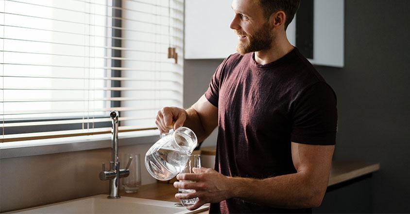 man pouring himself a glass of water