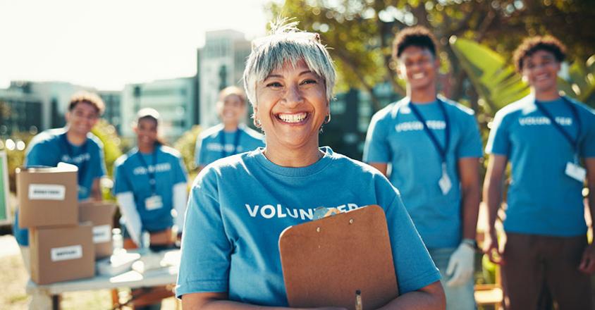 woman smiling with people behind her, all wearing "volunteer" blue t-shirts