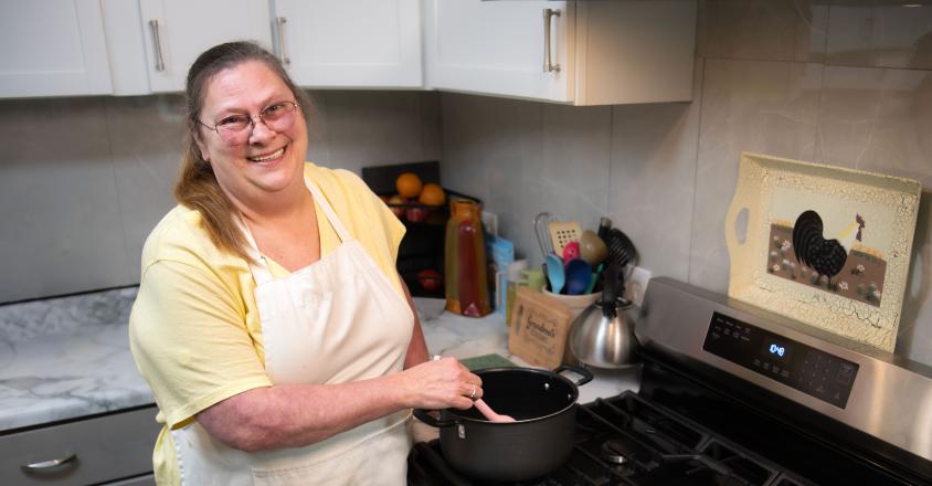 Genesis patient, Brenda Smith, cooking in her kitchen with a smile 