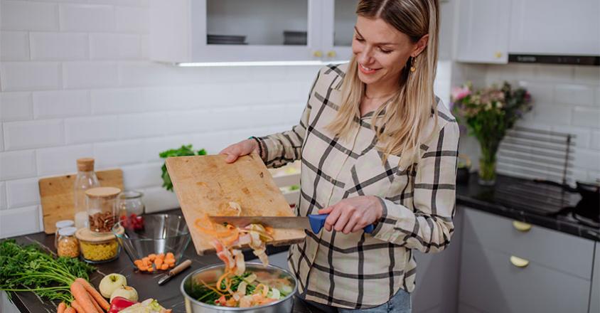 woman in kitchen making a healthy vegetable-filled salad