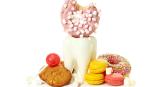 fake tooth statue with sweets surrounding, i.e. donuts, cookies, candy