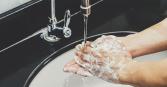 close up image of person washing soap off hands in sink