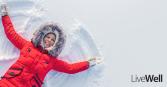 woman  making a snow angel with a smile and cozy jacket