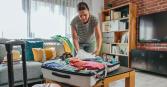 woman packing for vacation in living room with suitcase open and clothes folded inside