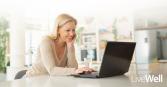 woman on her laptop, smiling in a kitchen at home