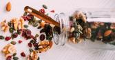 trail mix spilled over on counter with mason jar and spoon