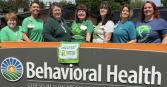 Genesis Behavioral Health sign with employees posing behind it in honor of Mental health awareness month 