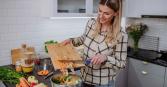woman in kitchen making a healthy vegetable-filled salad