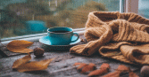 A cup of coffee sits by a window on a rainy day, complemented by a warm, knitted scarf and fallen leaves scattered on the wooden table. The tranquil scene evokes a sense of comfort and relaxation, ideal for projects centered on cozy moments, seasonal changes, or comforting beverages.
