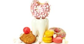 fake tooth statue with sweets surrounding, i.e. donuts, cookies, candy