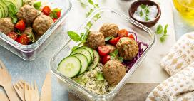 Table of healthy food options including meatballs, rice, cucumber and tomato