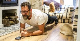 man doing a plank in his living room with dog laying near him