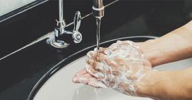 close up image of person washing soap off hands in sink