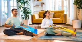 man and woman using stretching bands to stretch legs in living room