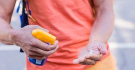 zoom in of man spraying sunscreen on his hand