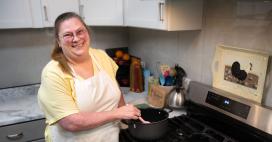Genesis patient, Brenda Smith, cooking in her kitchen with a smile 