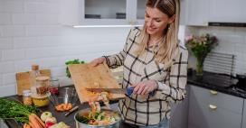 woman in kitchen making a healthy vegetable-filled salad