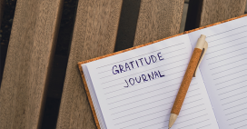 aerial view of a journal with "gratitude journal" written on the page with pen on top