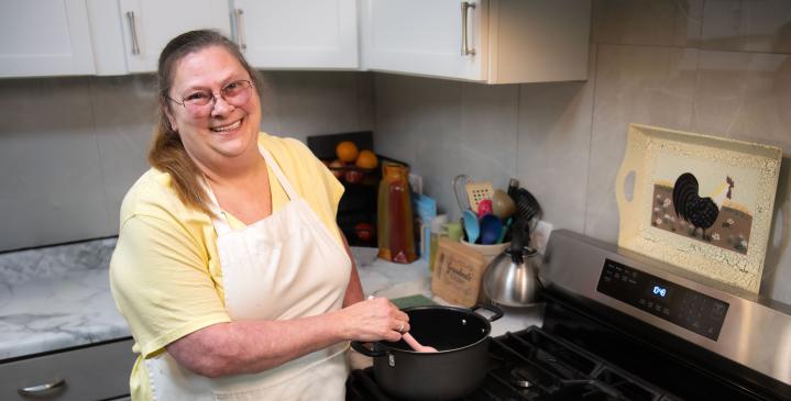Genesis patient, Brenda Smith, cooking in her kitchen with a smile 