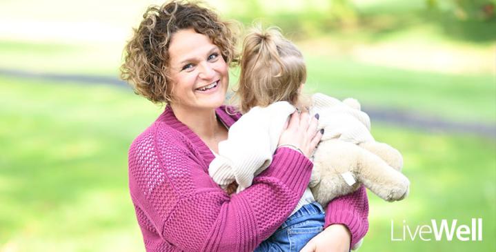 Genesis Cancer Care Center patient, Natalie Thompson, smiling with her 2 year old baby girl in her arms, in a bright setting outside